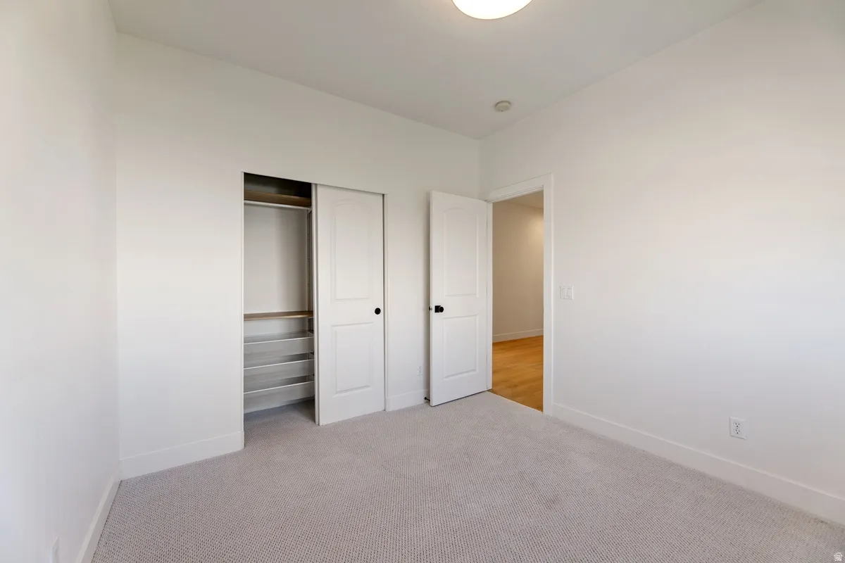 Unfurnished bedroom featuring light colored carpet and a closet