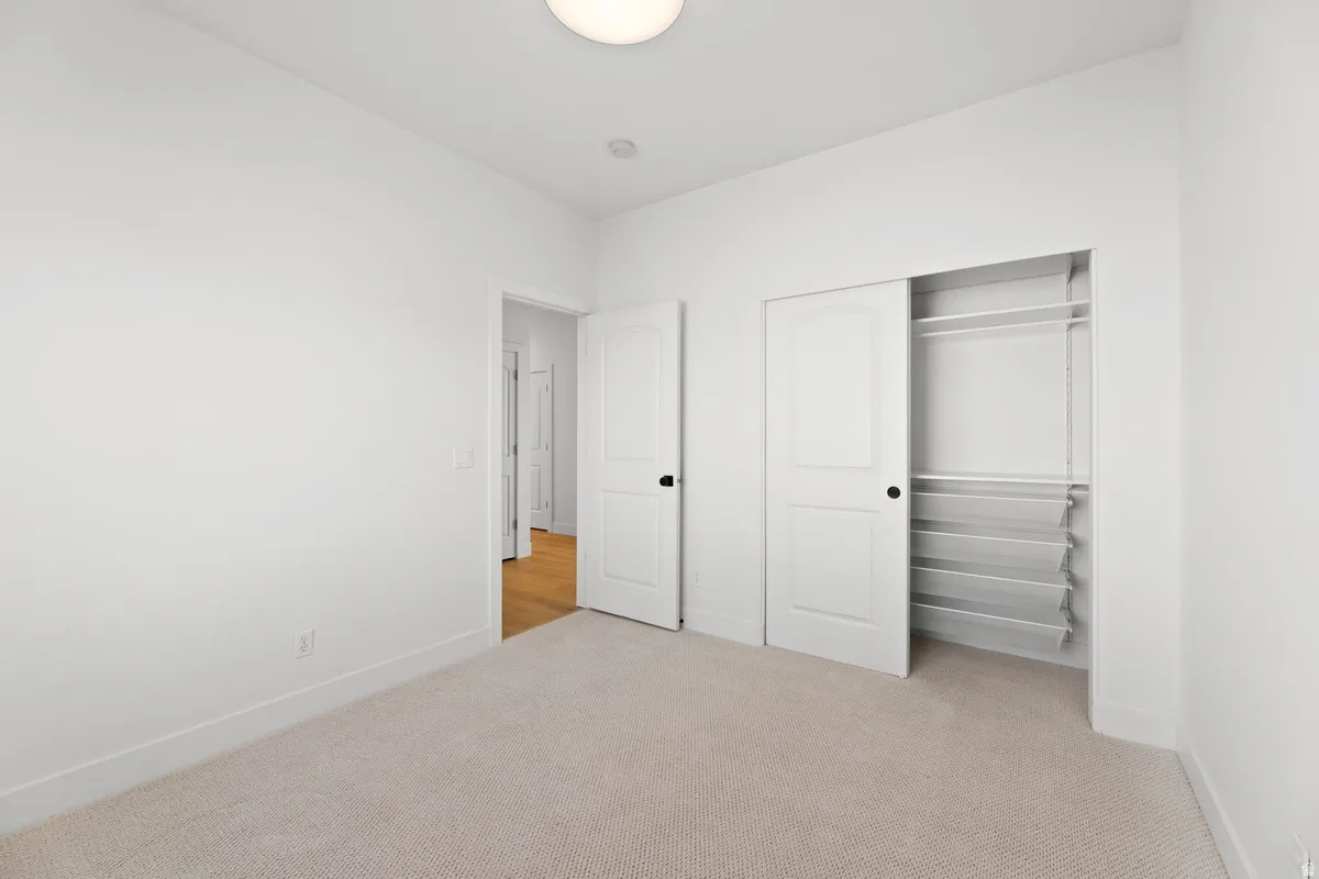 Unfurnished bedroom featuring light carpet and a closet