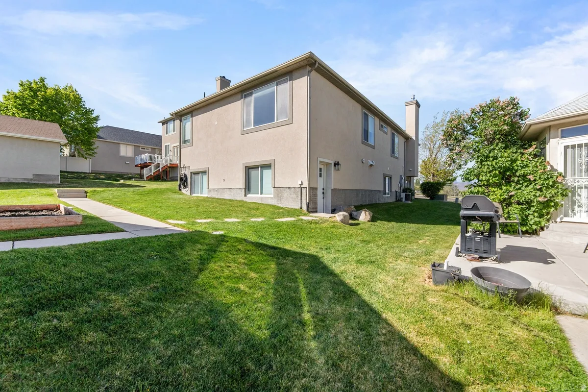 Back of house with a chimney, stucco siding, and a lawn