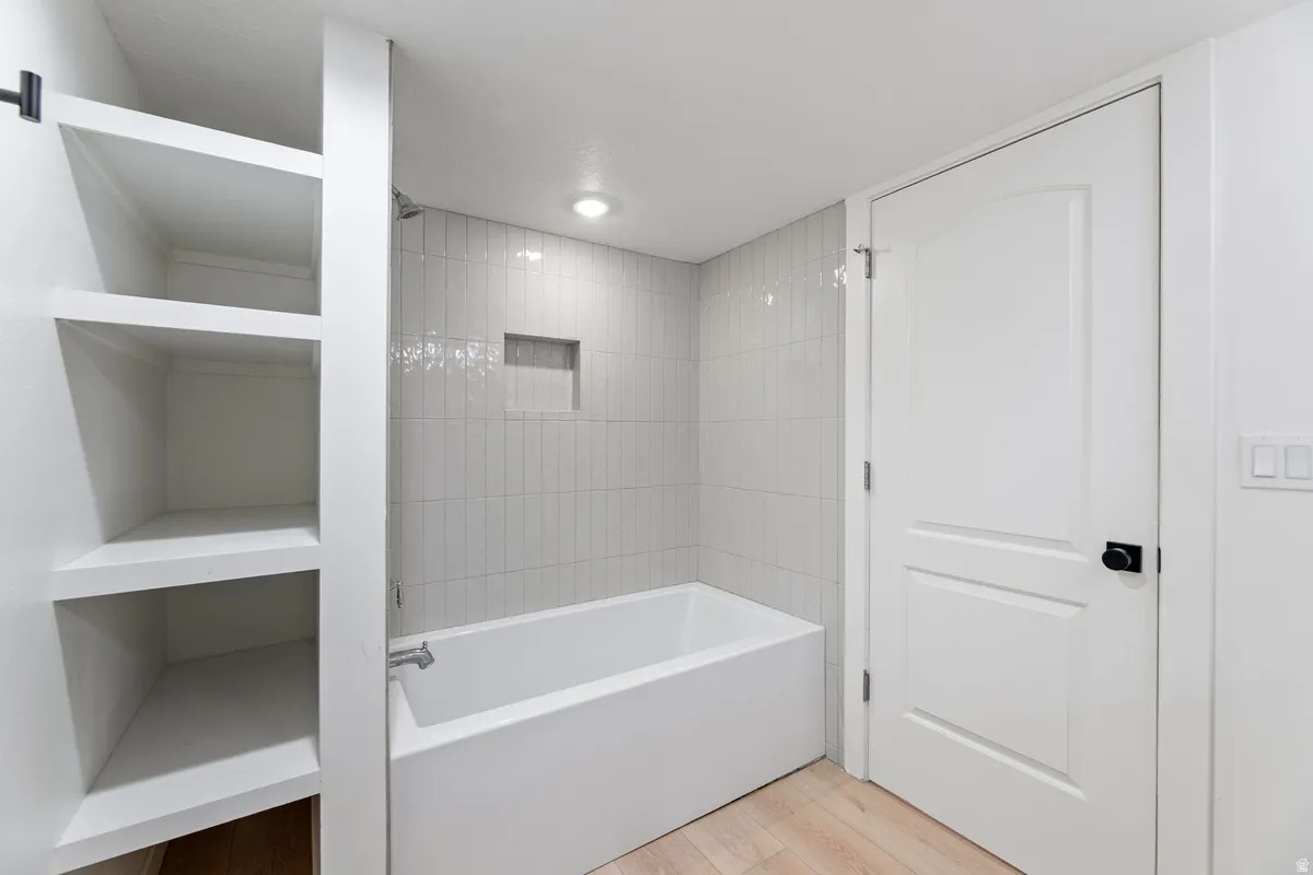 Bathroom with light wood finished floors, shower / washtub combination, and a closet