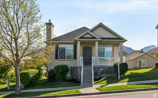 View of front of house featuring a front yard, covered porch, a chimney, and stucco siding