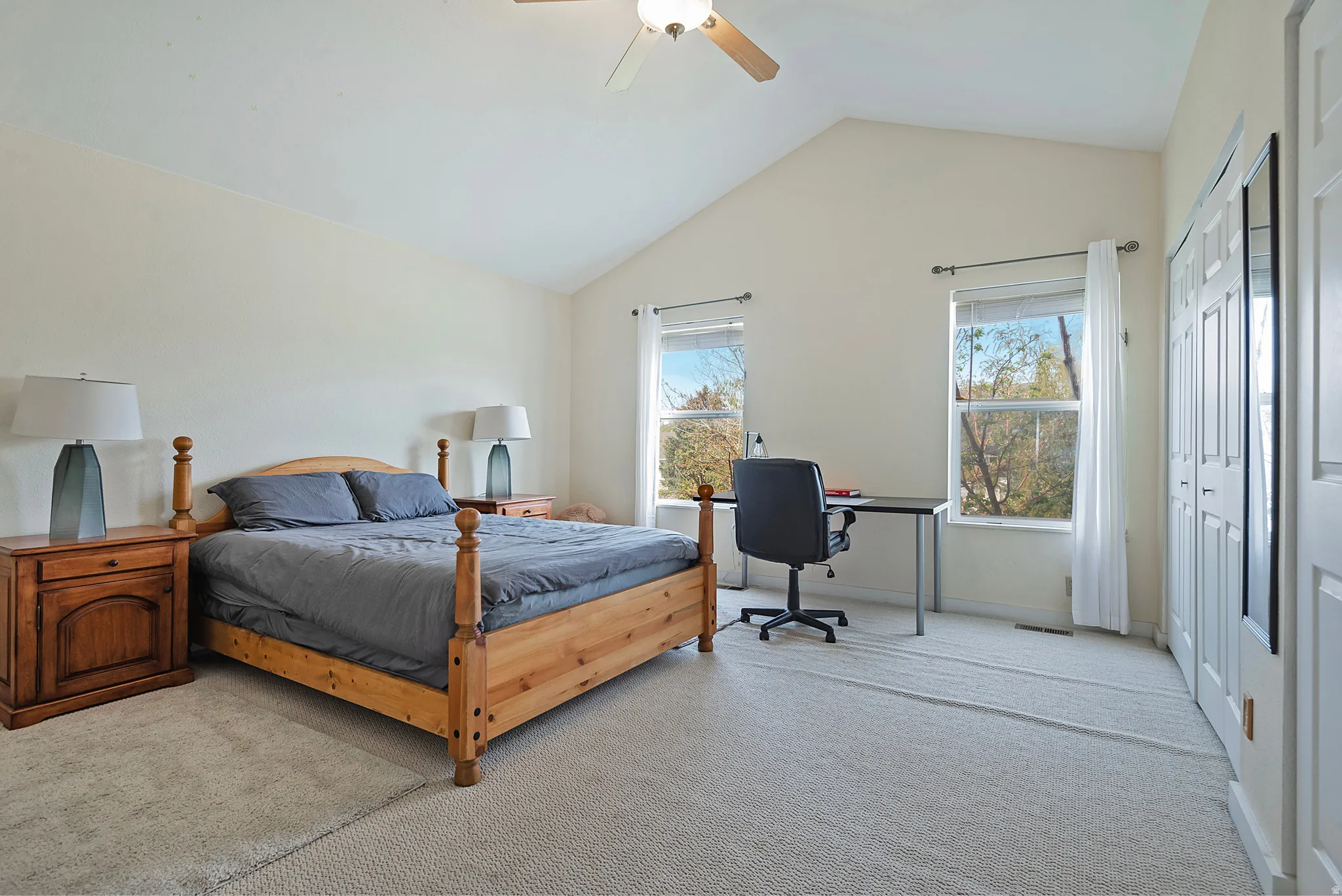 Bedroom with light colored carpet, a ceiling fan, a closet, and a desk