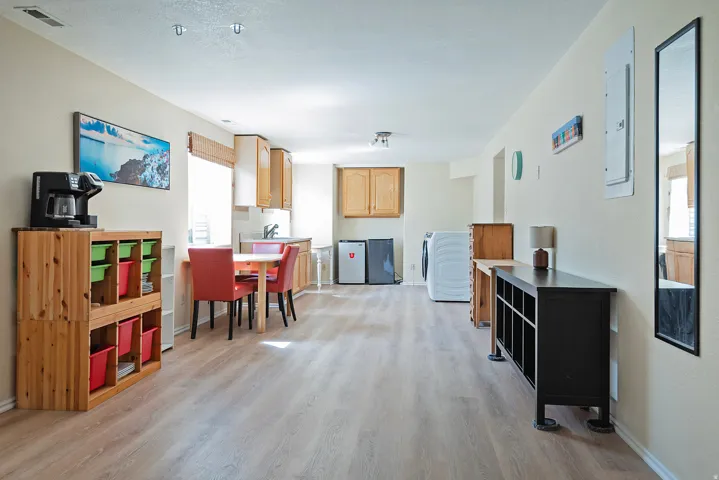 Kitchen with light wood-style floors, washer / clothes dryer, electric panel, light wood finish cabinets, and light countertops