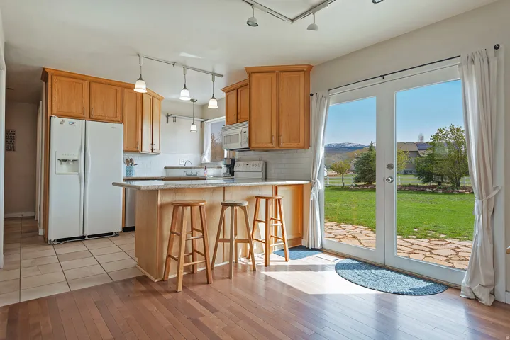 Kitchen with white appliances, a kitchen bar, a peninsula, rail lighting, and tasteful backsplash