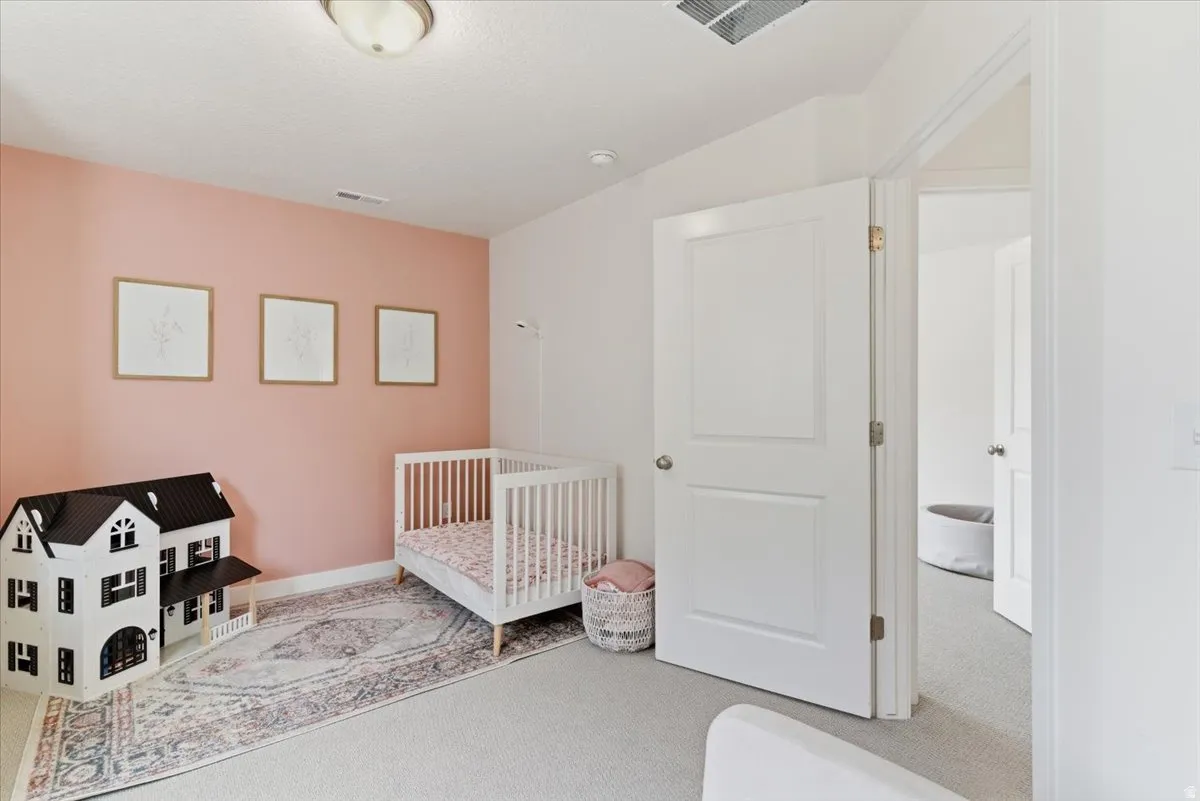 Bedroom featuring light carpet and a crib