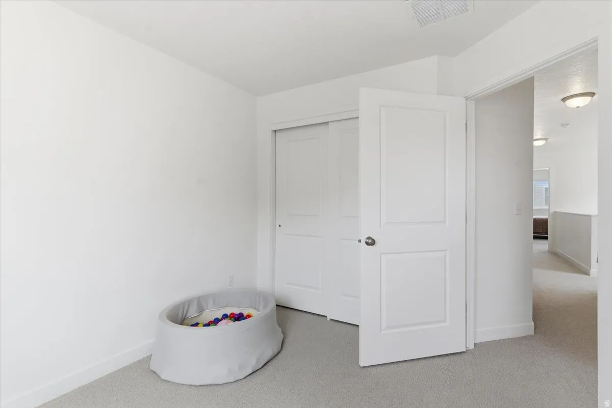 Unfurnished bedroom featuring light carpet and a closet