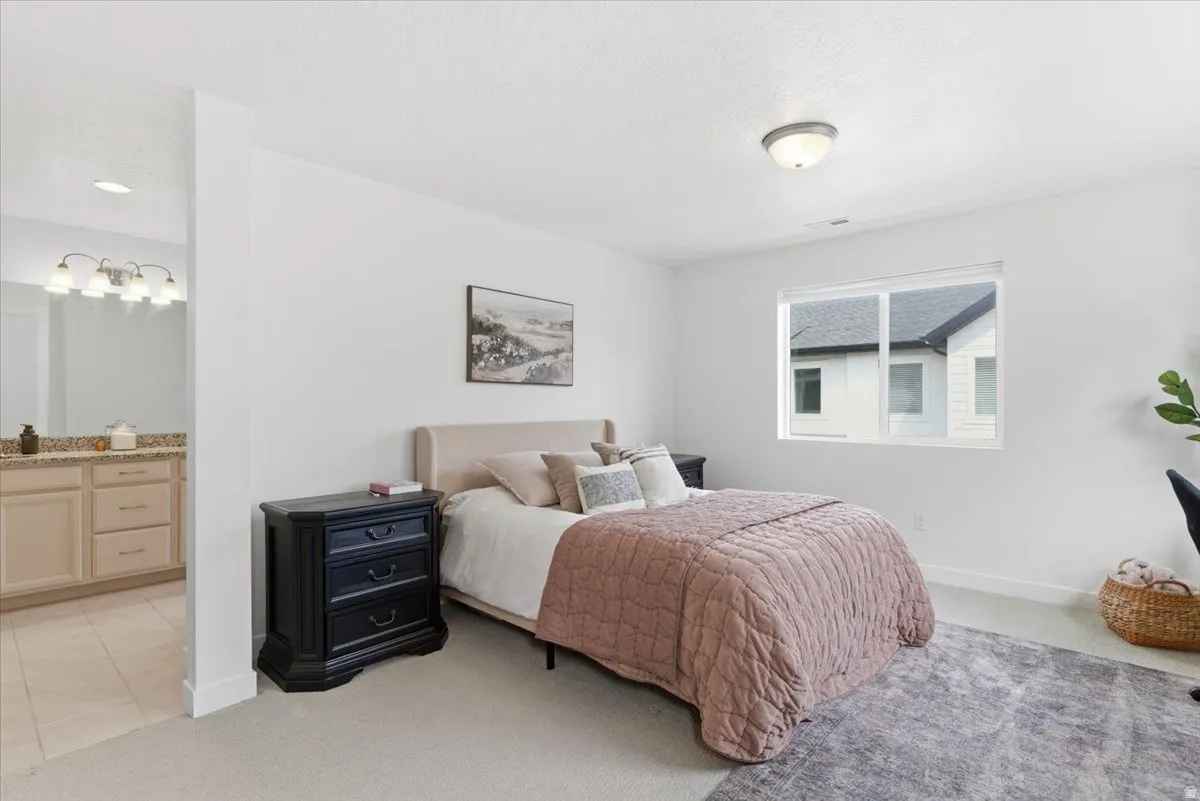 Bedroom with light carpet and connected bathroom