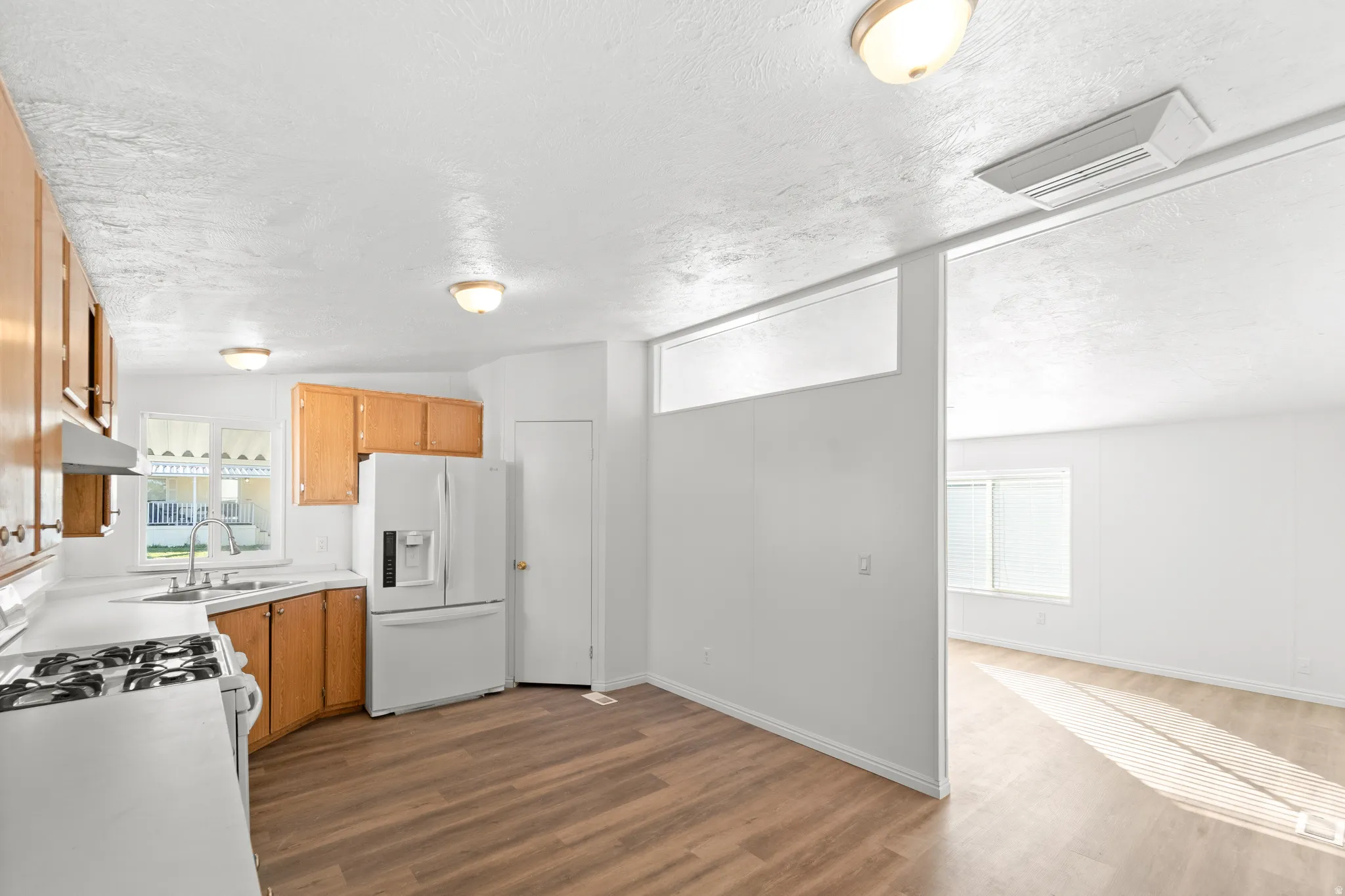 Kitchen featuring white appliances, light countertops, dark wood-style flooring, and cooling unit