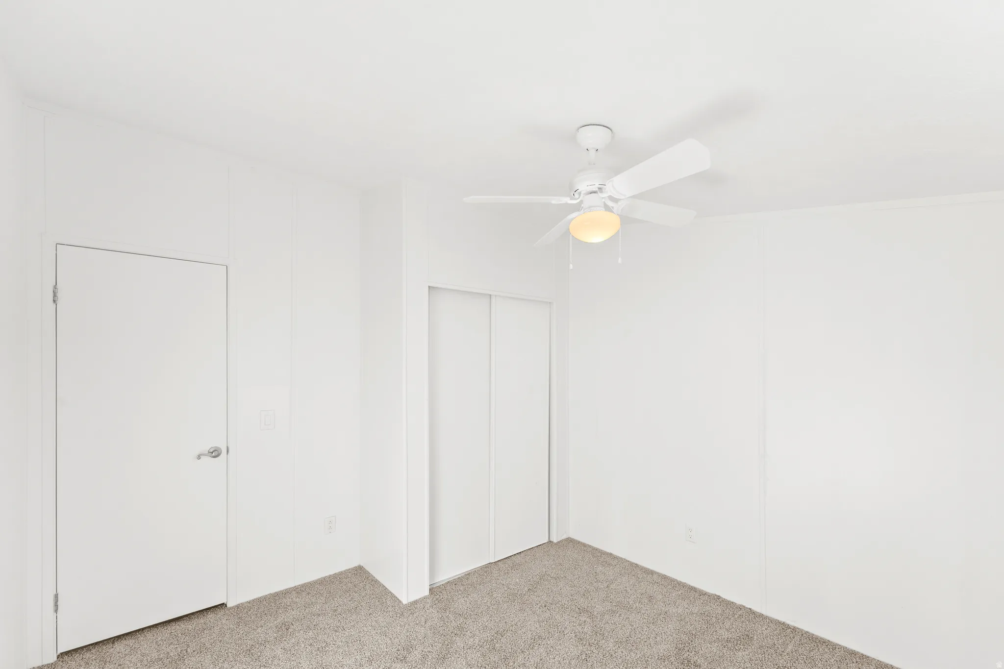 Unfurnished bedroom with light carpet, ceiling fan, and a closet