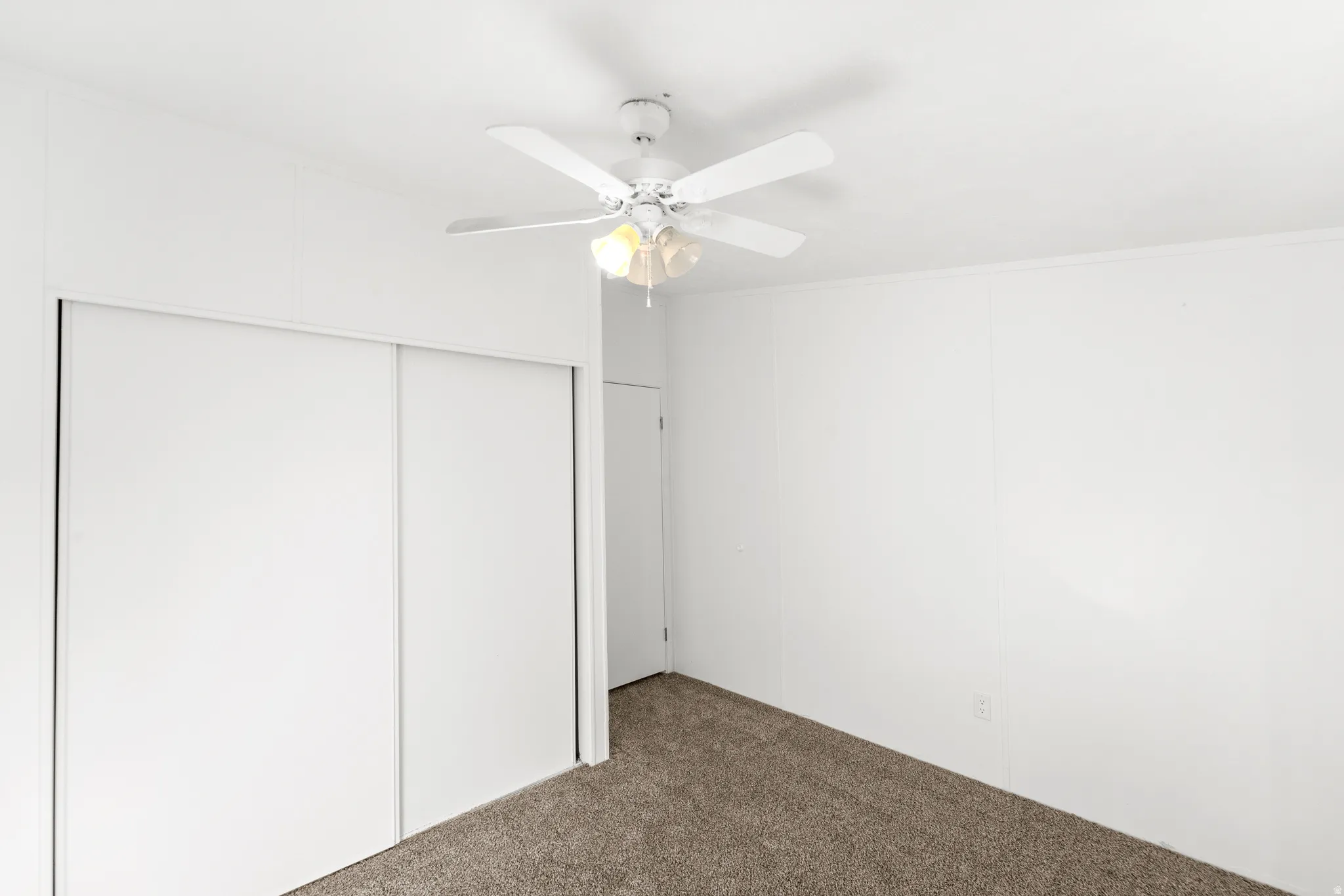 Unfurnished bedroom featuring carpet floors, ceiling fan, and a closet