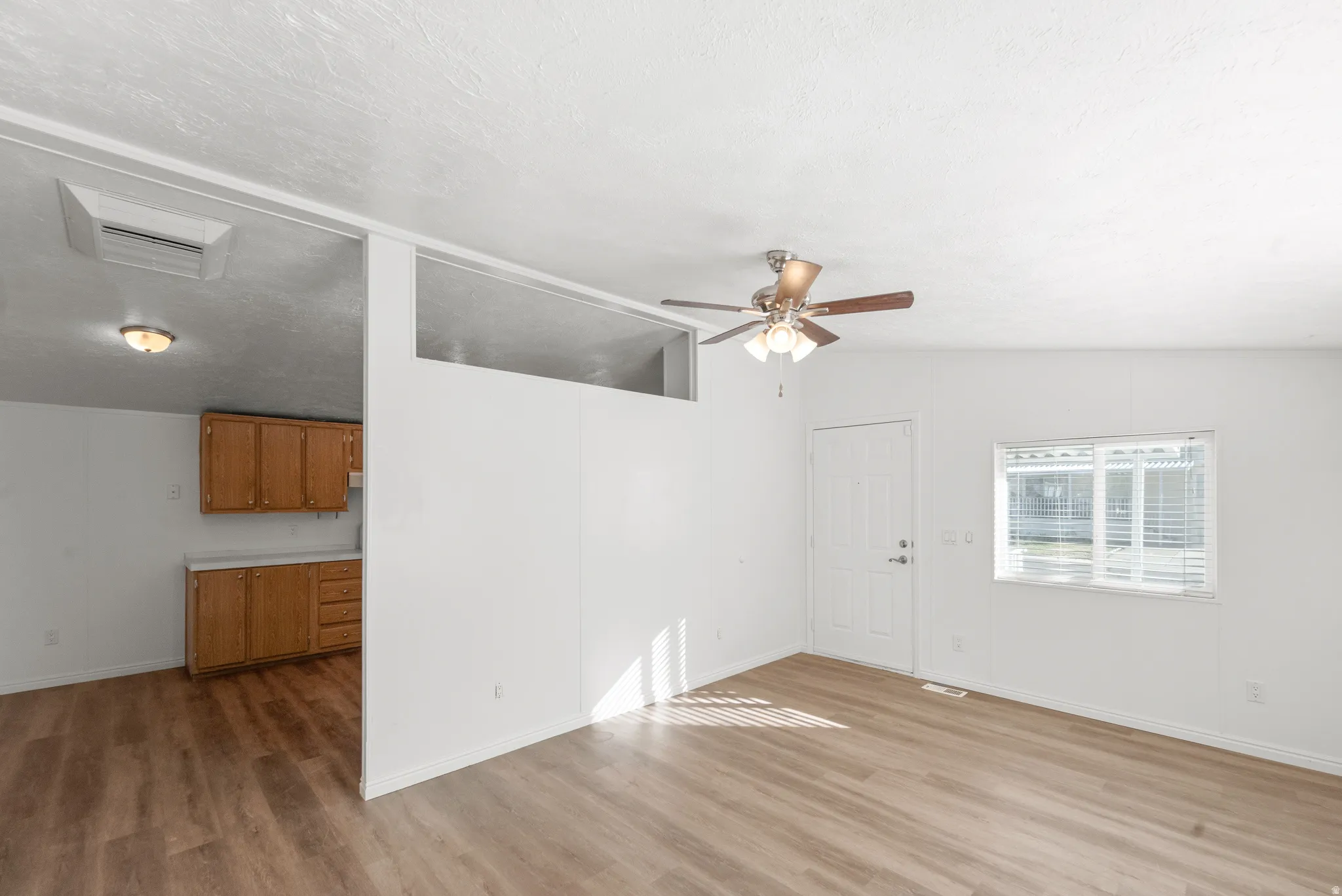 Unfurnished living room with a ceiling fan, light wood finished floors, and cooling unit