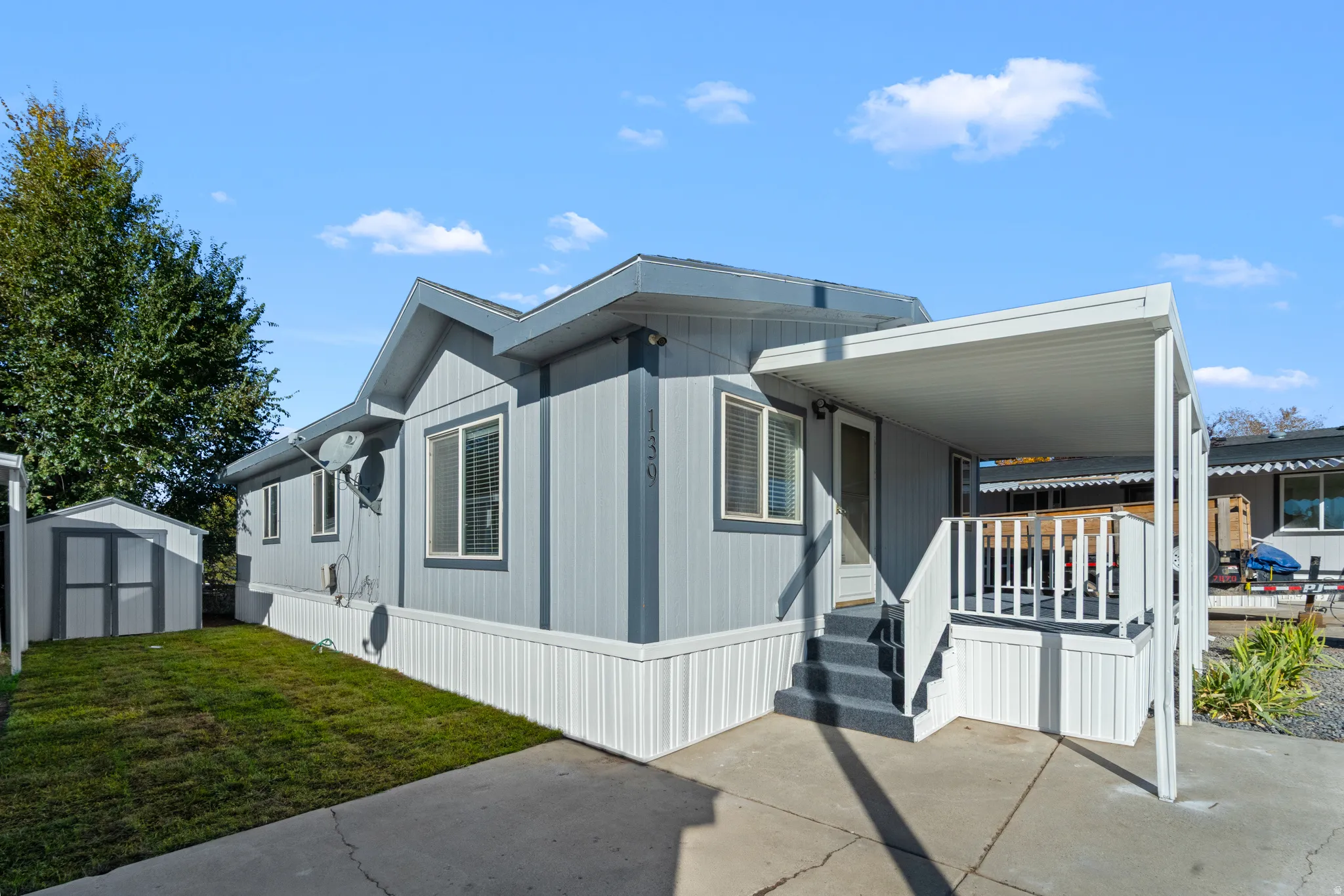 View of front facade featuring a front yard, a storage unit, and a porch