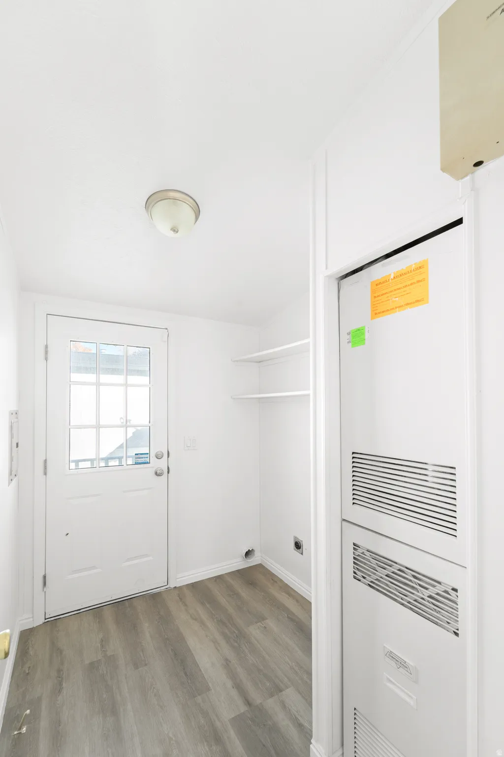 Laundry room with a heating unit and light wood-type flooring