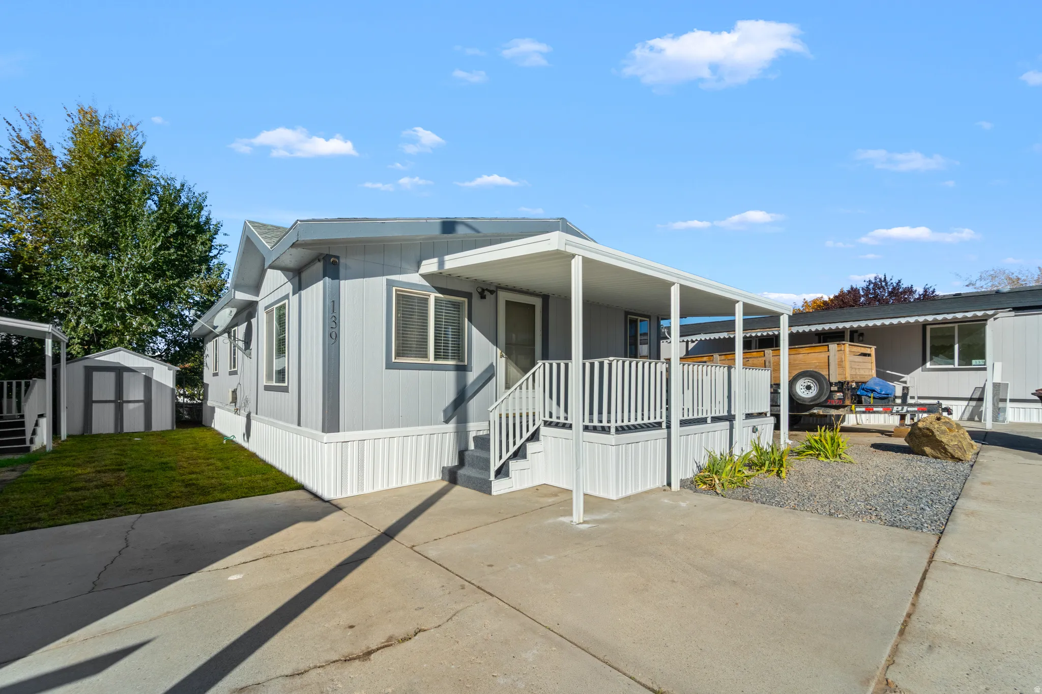 Manufactured / mobile home featuring a storage shed, an attached carport, a porch, and concrete driveway
