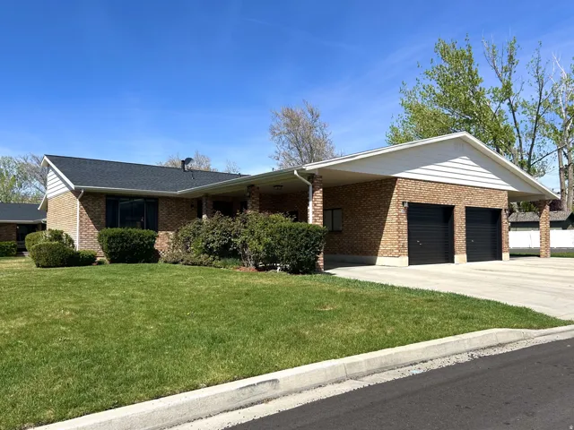 Ranch-style house featuring a front lawn, concrete driveway, brick siding, and a garage
