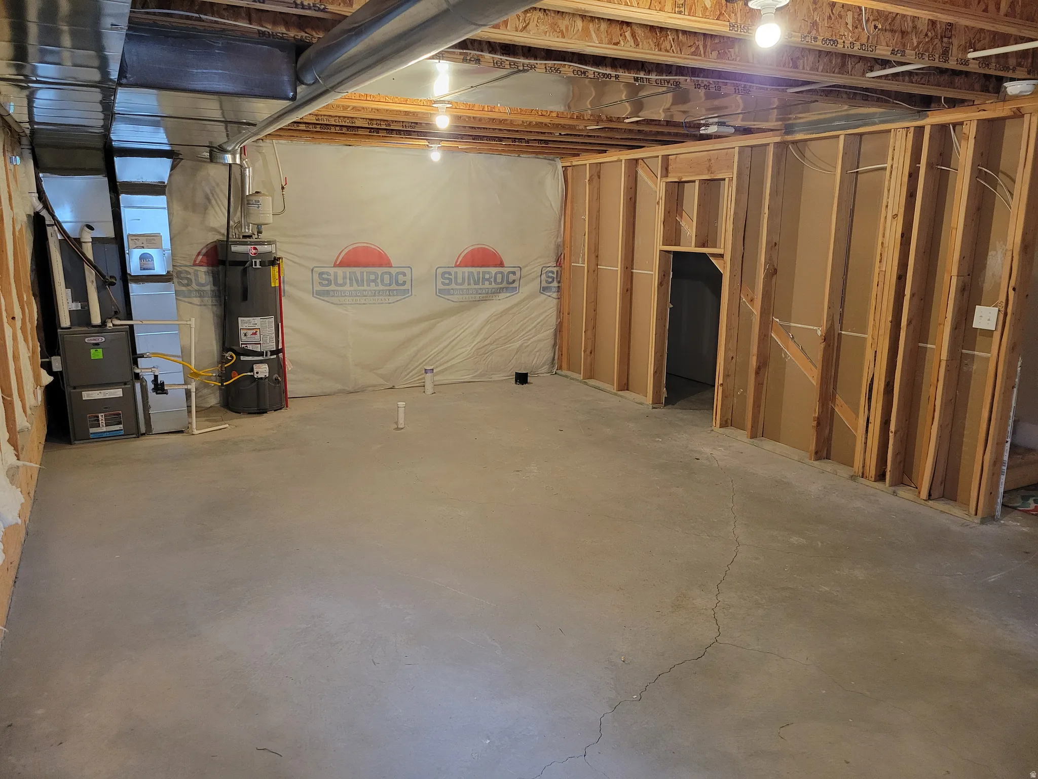 Unfinished below grade area featuring strapped water heater and heating unit