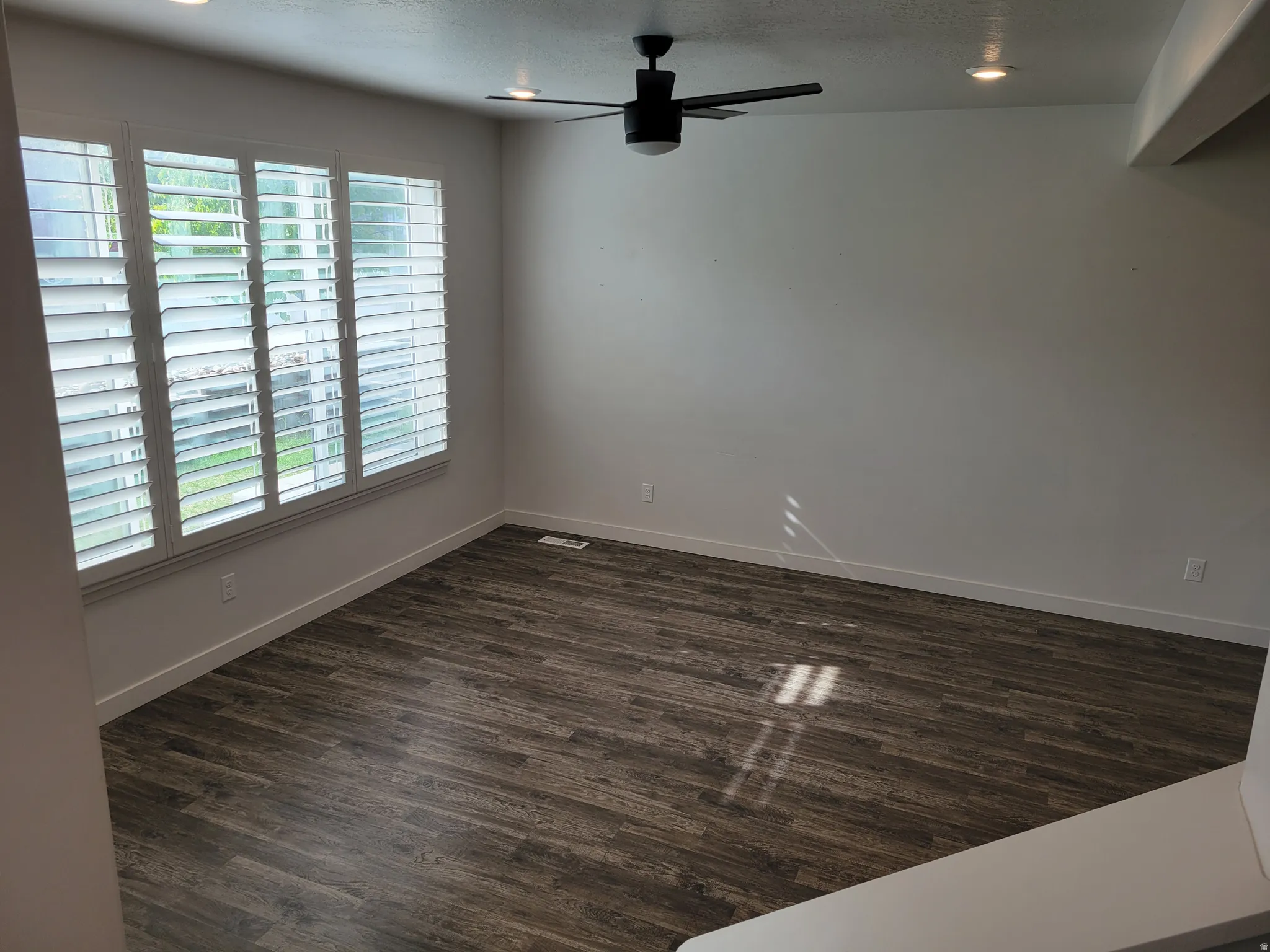 Spare room with ceiling fan, dark wood-style flooring, a textured ceiling, and recessed lighting