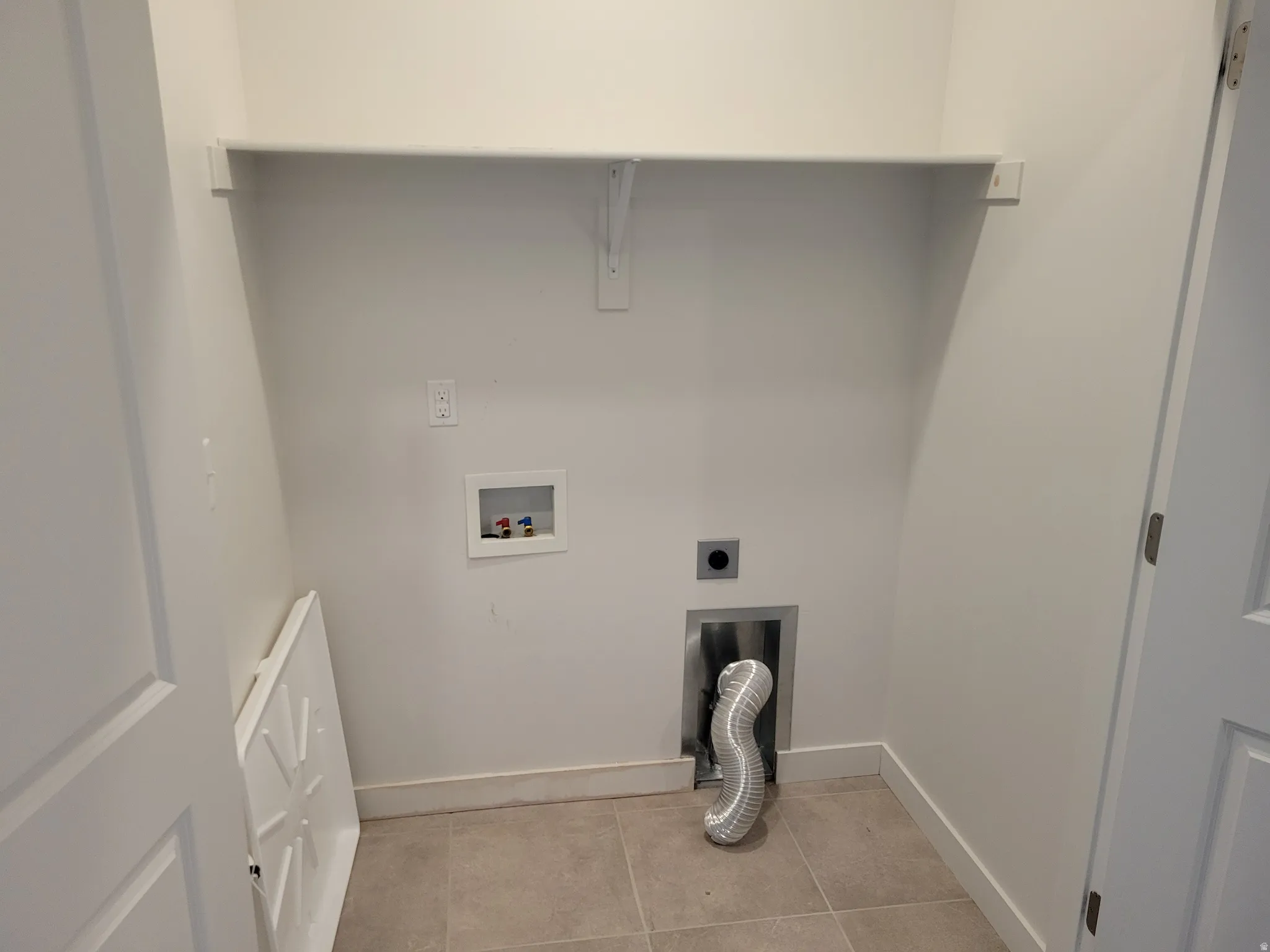 Laundry area with washer hookup, light tile patterned floors, and hookup for an electric dryer
