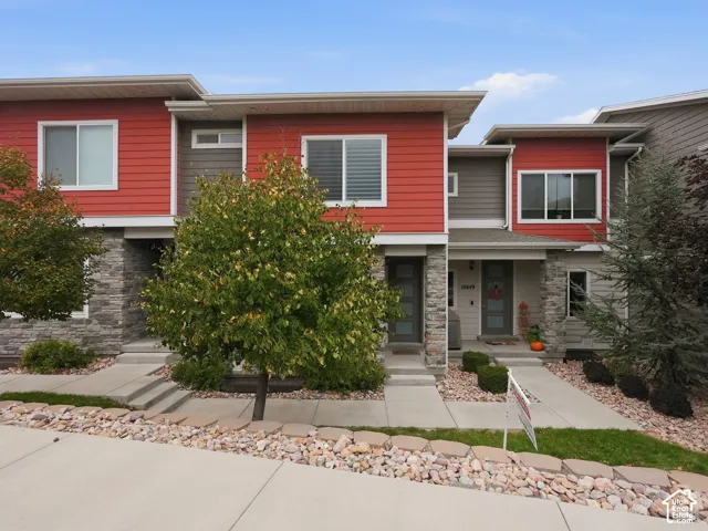 Multi-level exterior featuring horizontal siding, stone veneer accents, recessed entryways, and concrete walkways