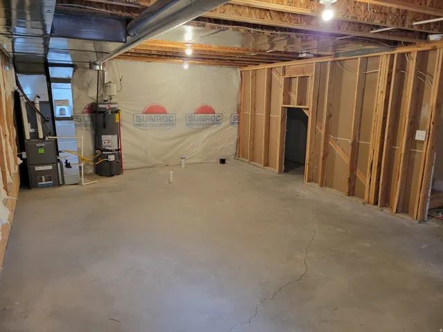 Unfinished below grade area featuring strapped water heater and heating unit