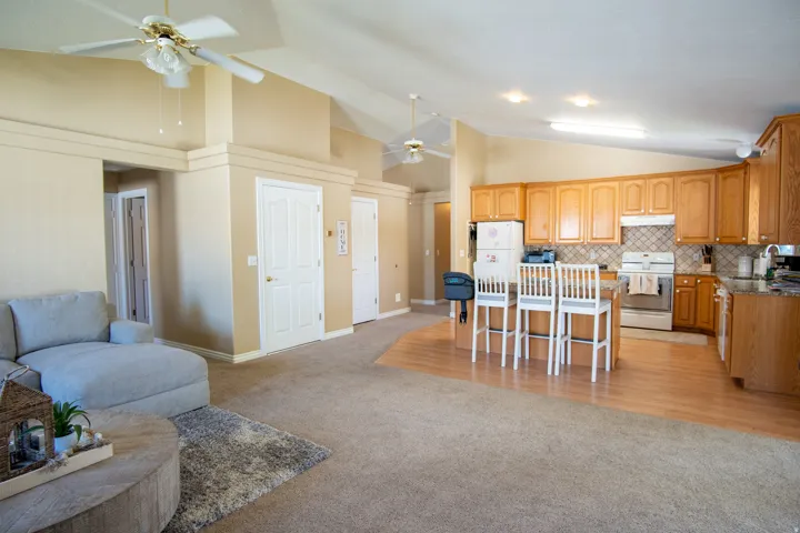 Kitchen featuring open floor plan, white appliances, light carpet, a center island, and ceiling fan