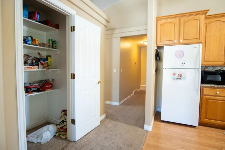 Kitchen with freestanding refrigerator, black microwave, light wood-type flooring, decorative backsplash, and light stone counters