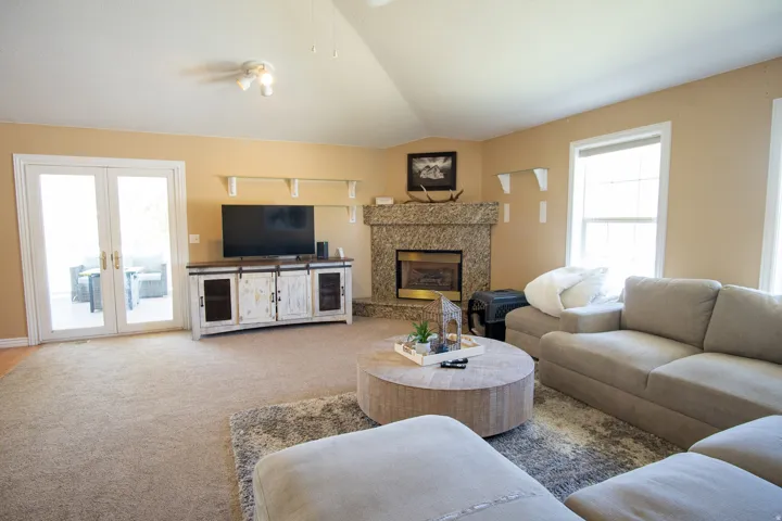 Carpeted living room featuring plenty of natural light, lofted ceiling, french doors, and a fireplace