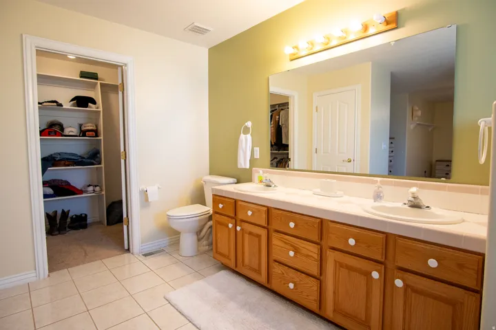 Bathroom featuring a walk in closet, double vanity, and light tile patterned flooring