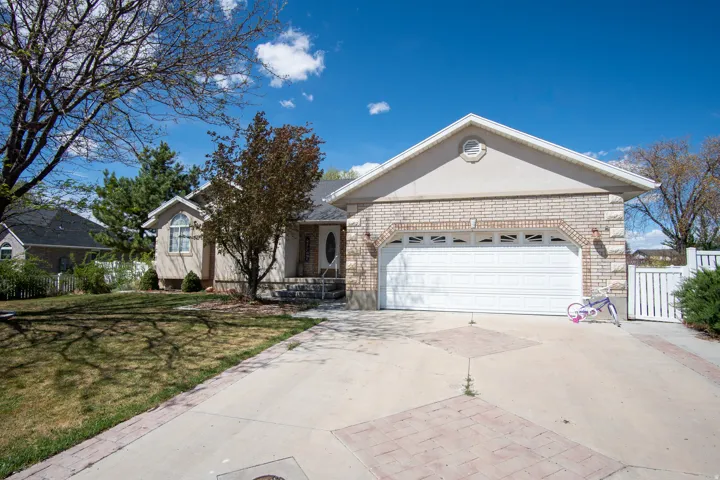 Ranch-style house featuring driveway, brick siding, an attached garage, and stucco siding