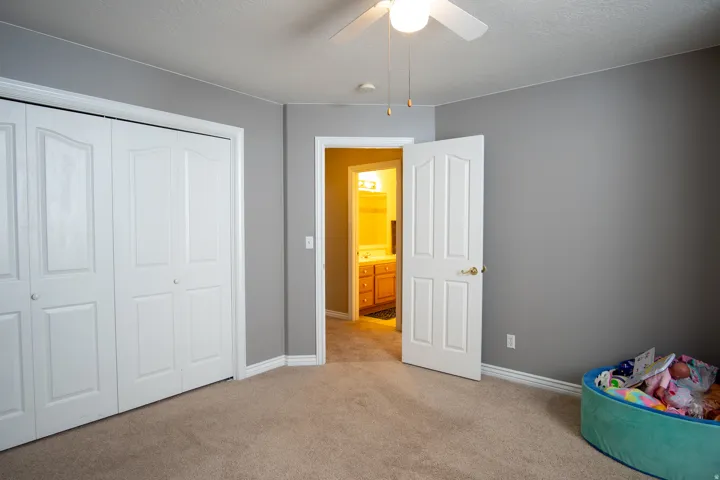 Unfurnished bedroom with light carpet, a textured ceiling, a closet, and ceiling fan
