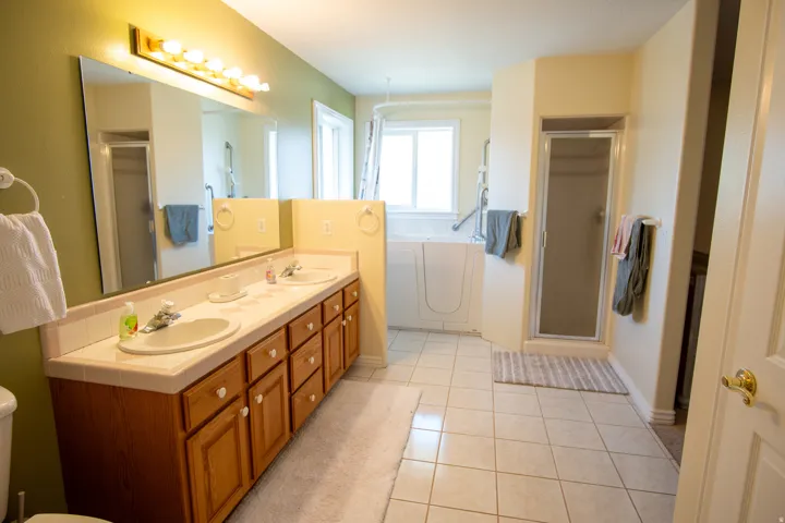 Full bath with a shower stall, double vanity, light tile patterned floors, and a garden tub