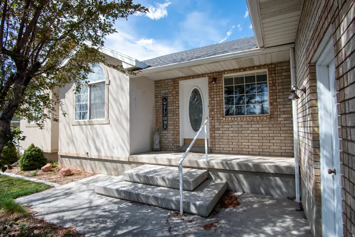 Entrance to property featuring brick siding, roof with shingles, and a patio area