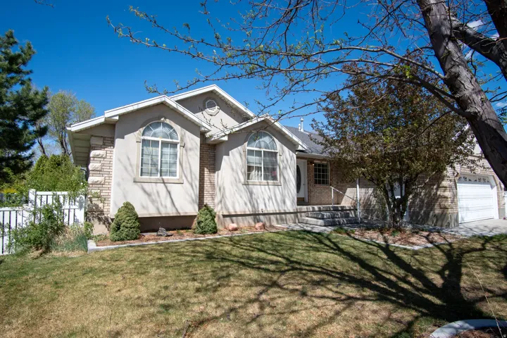 Ranch-style home featuring an attached garage, stucco siding, and brick siding