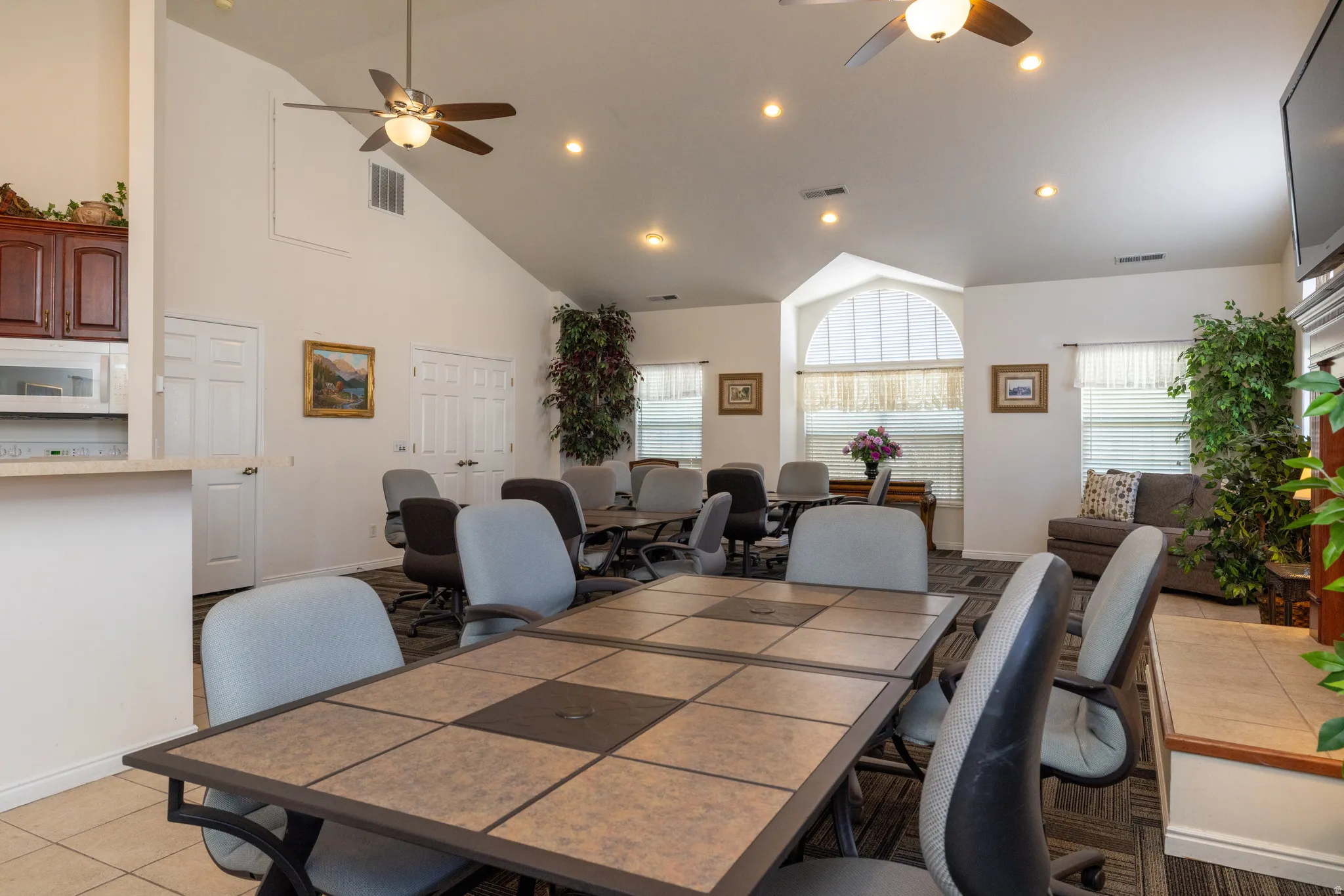 Community clubhouse space featuring a ceiling fan, light tile patterned flooring, vaulted ceiling, and recessed lighting