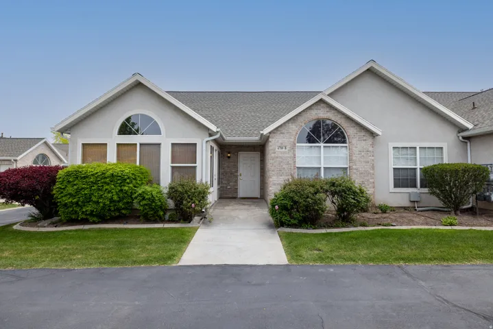 Ranch-style home featuring stucco siding, roof with shingles, brick siding, and a front lawn