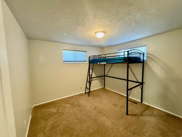 Unfurnished bedroom with a textured ceiling and carpet