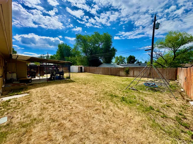 Expansive backyard featuring a covered patio, full perimeter wood fencing, and a separate storage shed