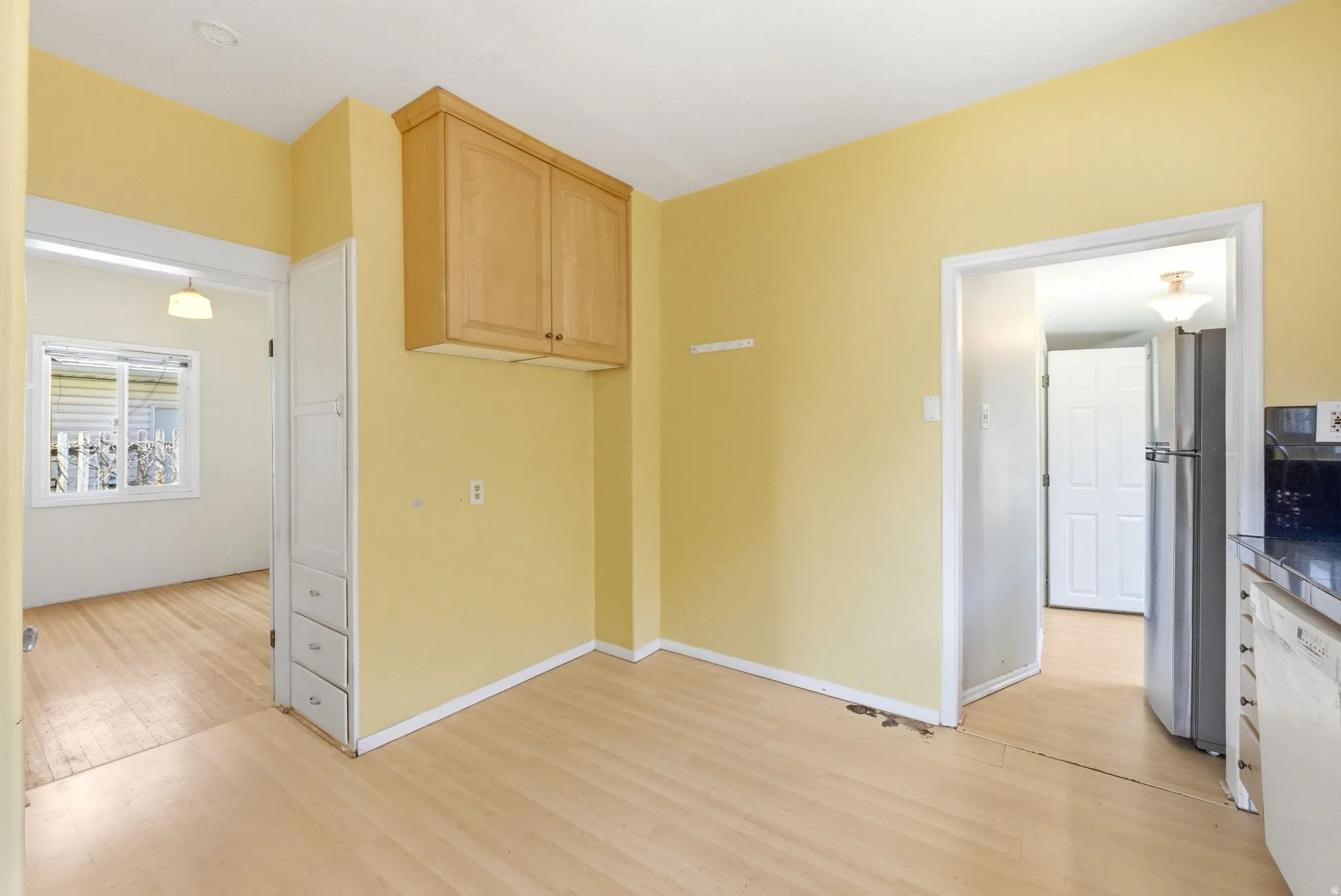 Kitchen with freestanding refrigerator, dishwasher, light wood-type flooring, and light wood finish cabinetry