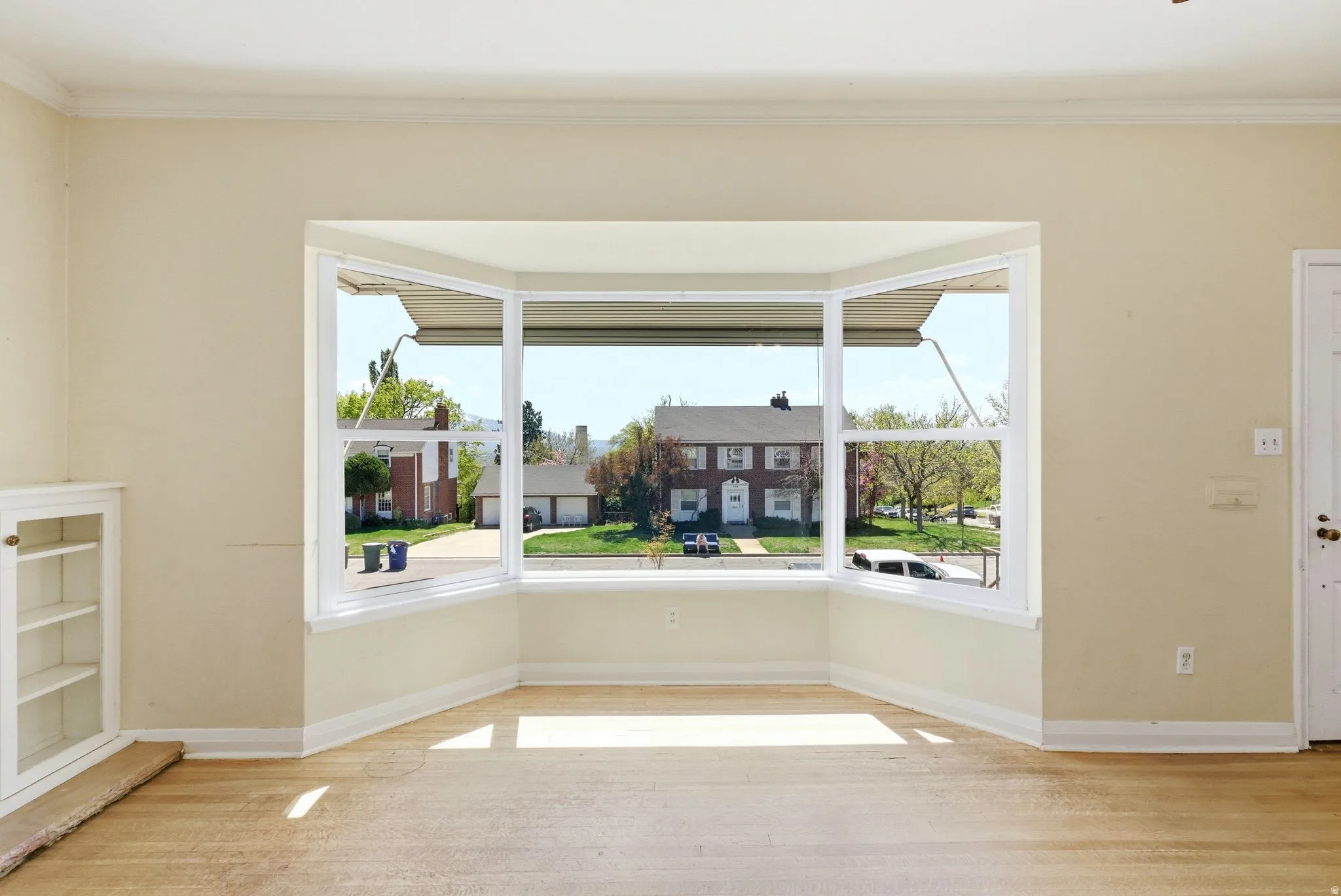 Unfurnished room with healthy amount of natural light, light wood-style floors, and ornamental molding