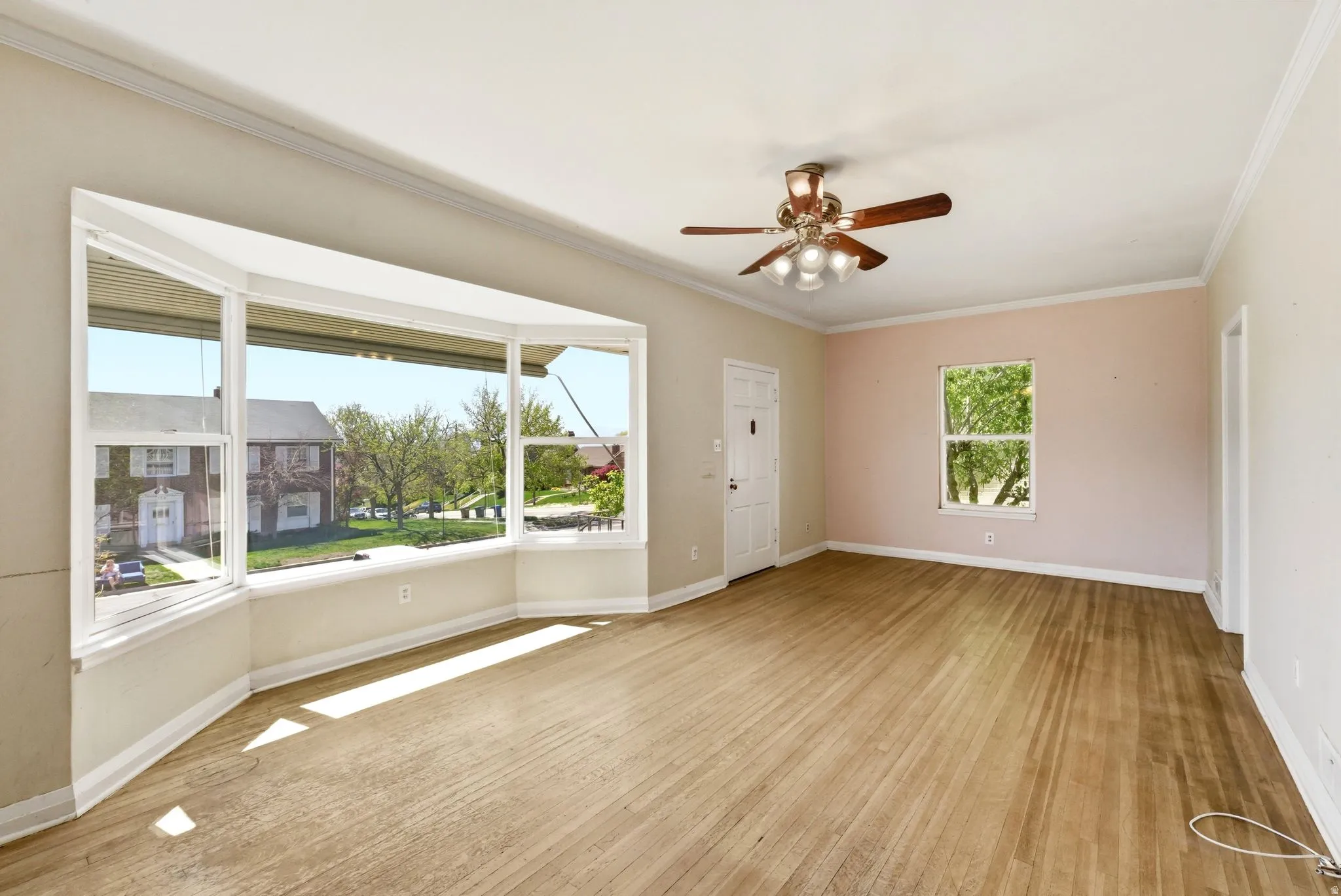 Spare room with light wood-style flooring, a ceiling fan, and ornamental molding