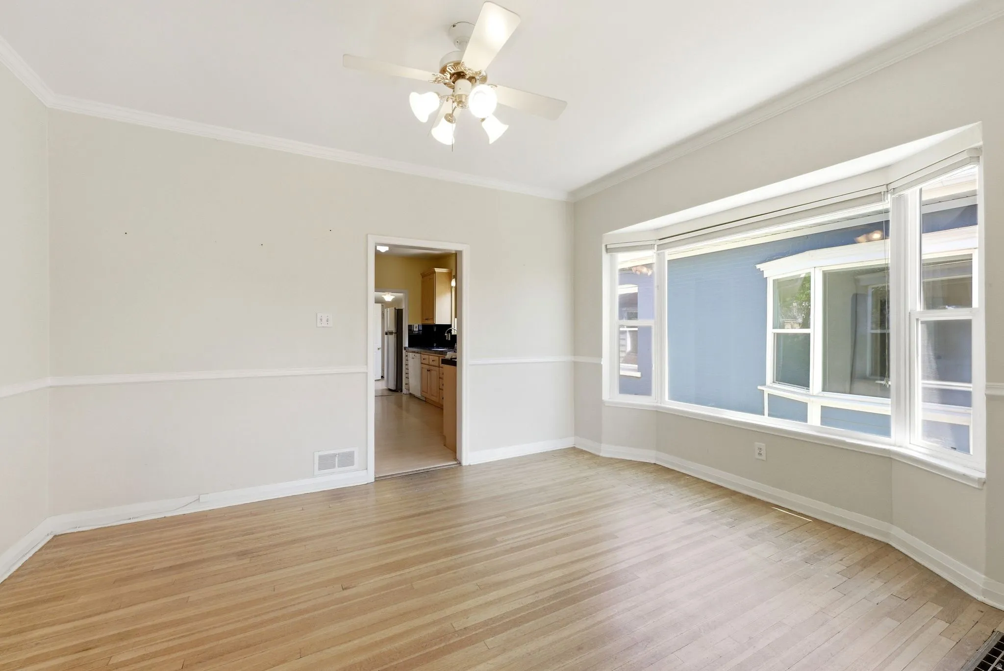 Unfurnished room with light wood finished floors, a ceiling fan, and ornamental molding