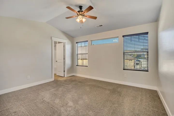 Unfurnished bedroom with lofted ceiling, light colored carpet, and a ceiling fan
