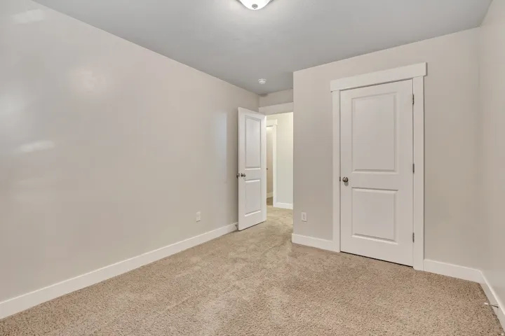 Unfurnished bedroom with baseboards and light carpet