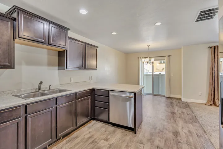 Kitchen with dark wood finish cabinets, dishwasher, a peninsula, a chandelier, and light wood-style floors