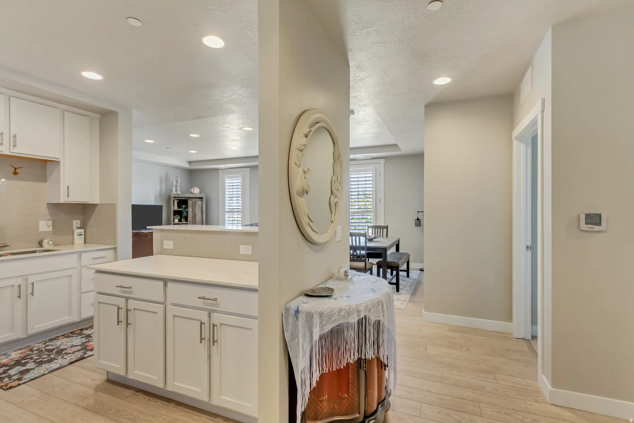 Kitchen with light wood-type flooring, white cabinetry, and recessed lighting