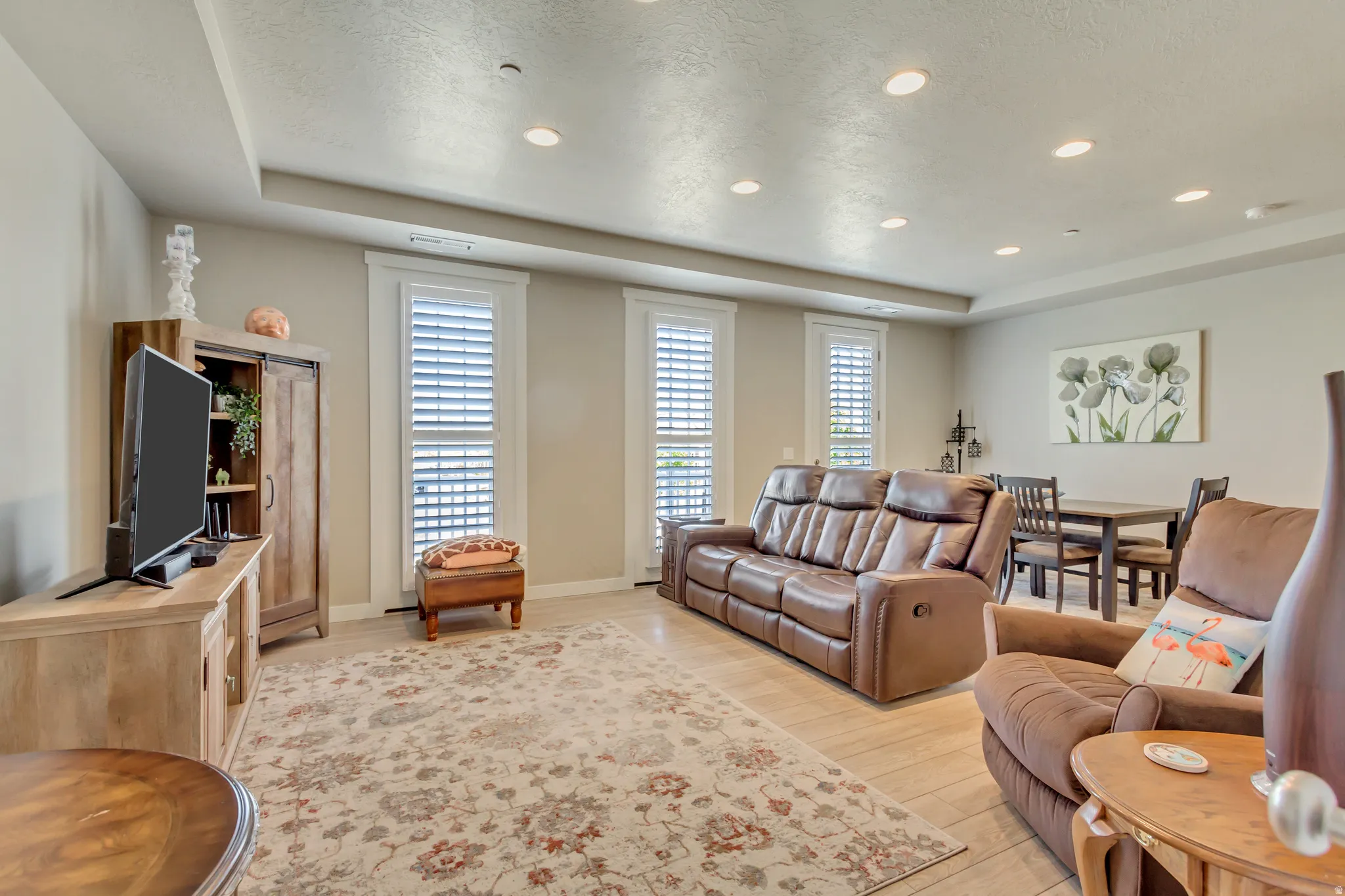 Living room featuring a tray ceiling, light wood-type flooring, recessed lighting, and a textured ceiling