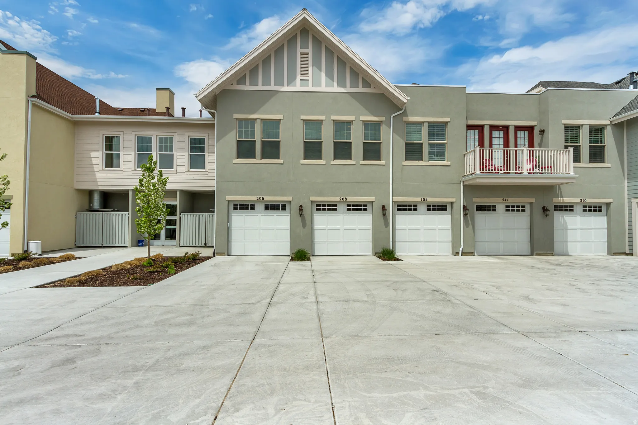 View of front of house with an attached garage, french doors, a balcony, stucco siding, and driveway