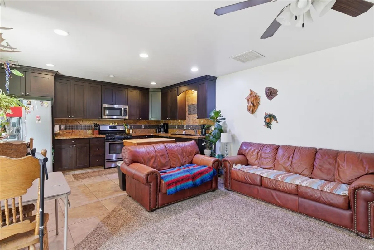 Living area with a ceiling fan, light tile patterned floors, and recessed lighting