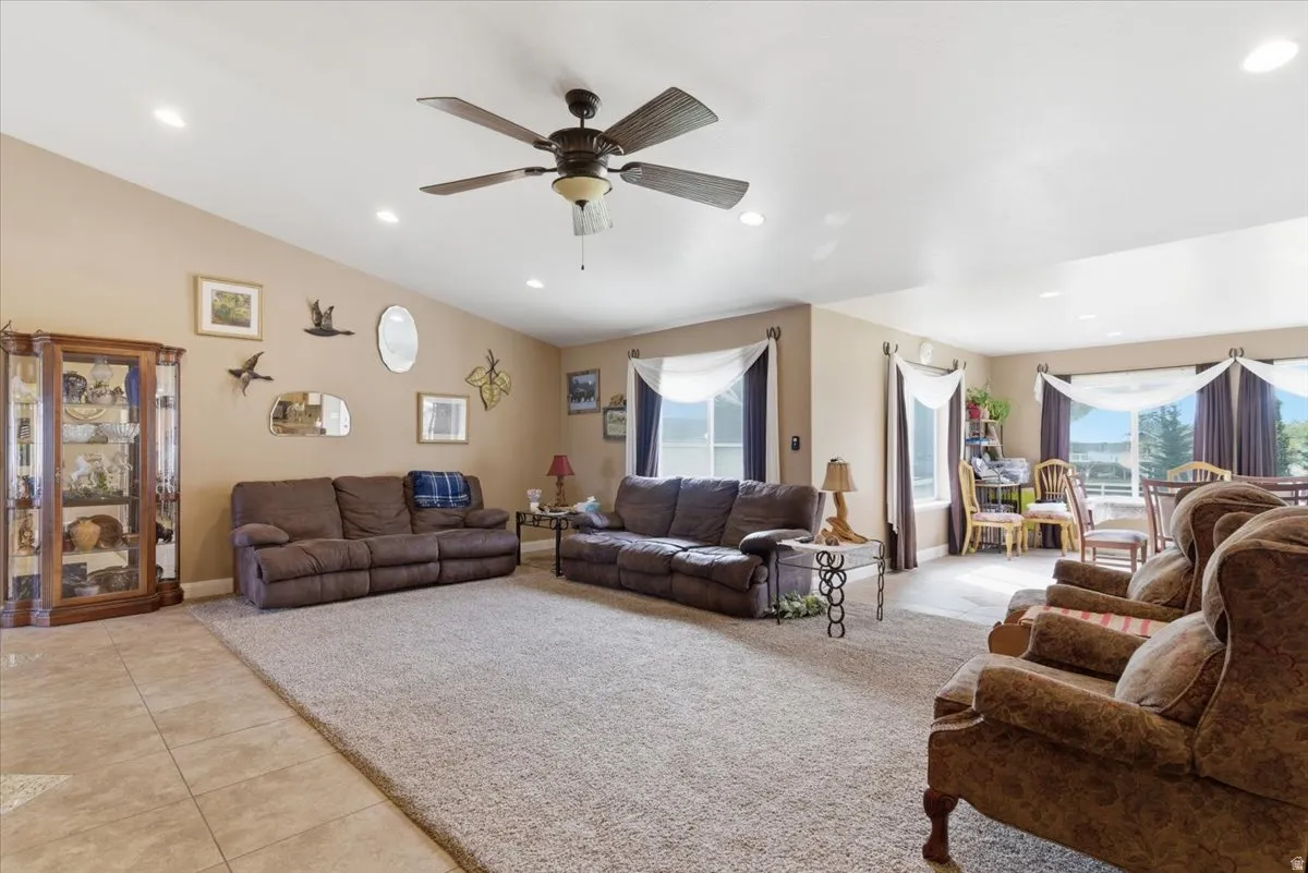 Living room with light tile patterned floors, ceiling fan, healthy amount of natural light, and recessed lighting