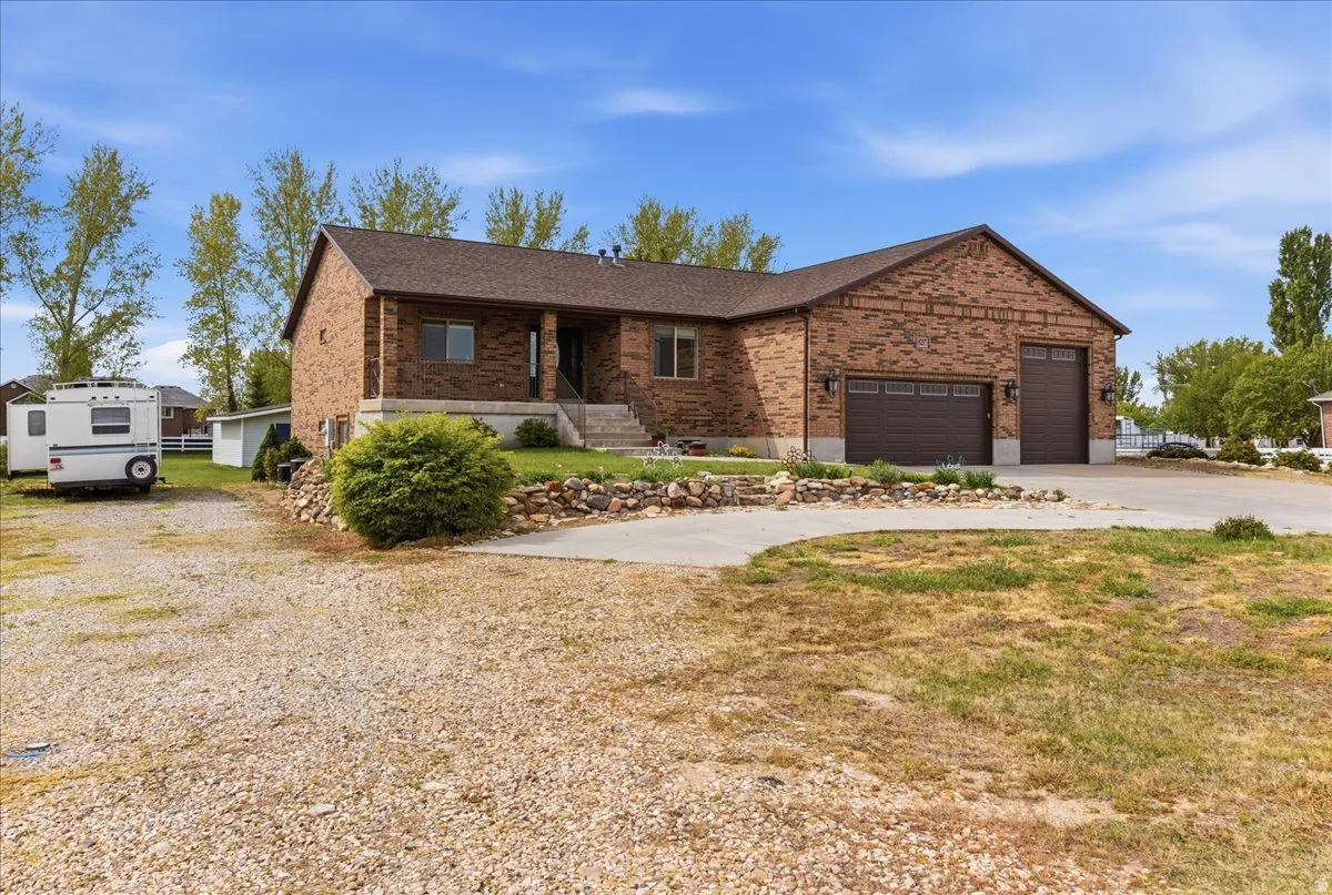 Ranch-style house featuring brick siding, concrete driveway, covered porch, a garage, and a shingled roof